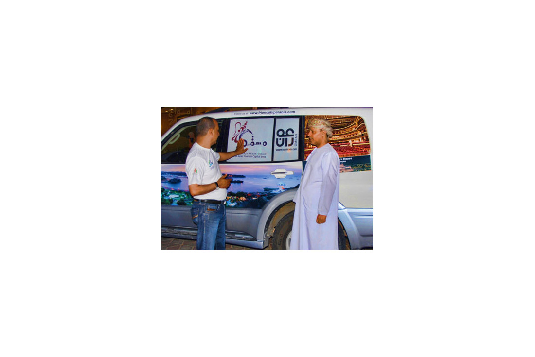 Ali showing Yahya Al Kiyumi the Oman images on the cars 