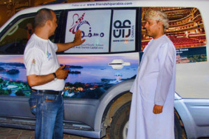 Ali showing Yahya Al Kiyumi the Oman images on the cars 